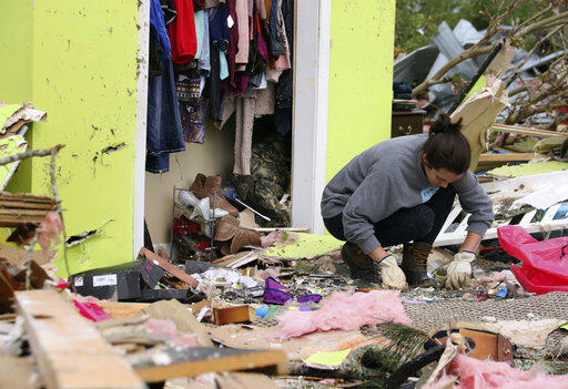 Leslie Harrington kneels down to help a former neighbor and family friend look for jewelry in her destroyed home along Seely Drive outside of Hamilton, Miss., after a deadly storm moved through the area on Sunday, April 14, 2019.