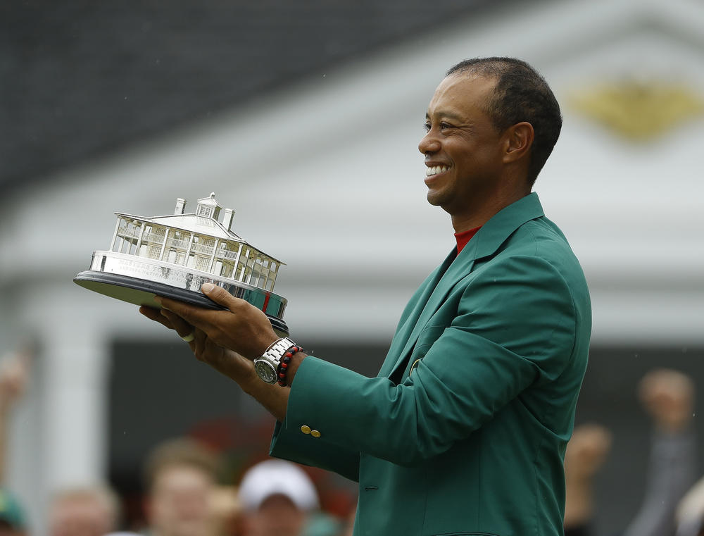 Tiger Woods wears his green jacket holding the winning trophy after the final round for the Masters golf tournament Sunday, April 14, 2019, in Augusta, Ga.