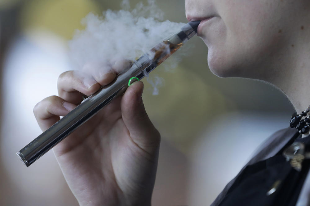 In this Friday, Oct. 4, 2019 photo, a woman using an electronic cigarette exhales in Mayfield Heights, Ohio.