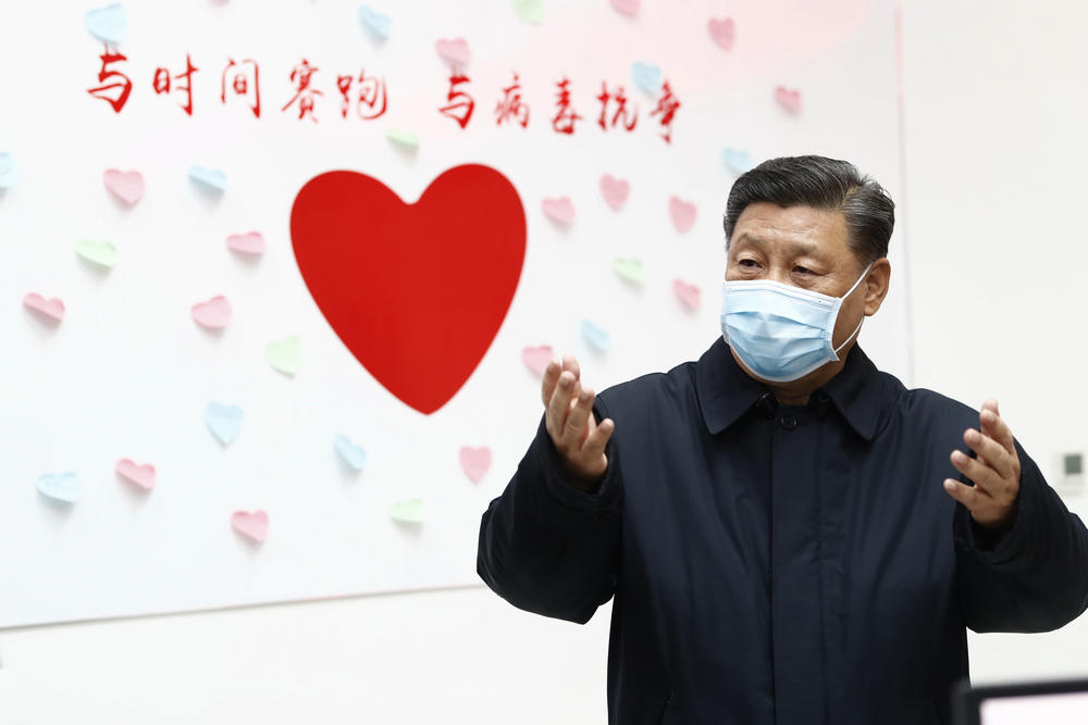 Chinese President Xi Jinping gestures near a heart shape sign and the slogan 