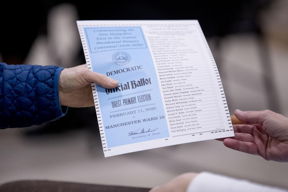 A woman takes a Democratic ballot to vote in the New Hampshire Primary at Parker-Varney Elementary School, Tuesday, Feb. 11, 2020, in Manchester, N.H. 