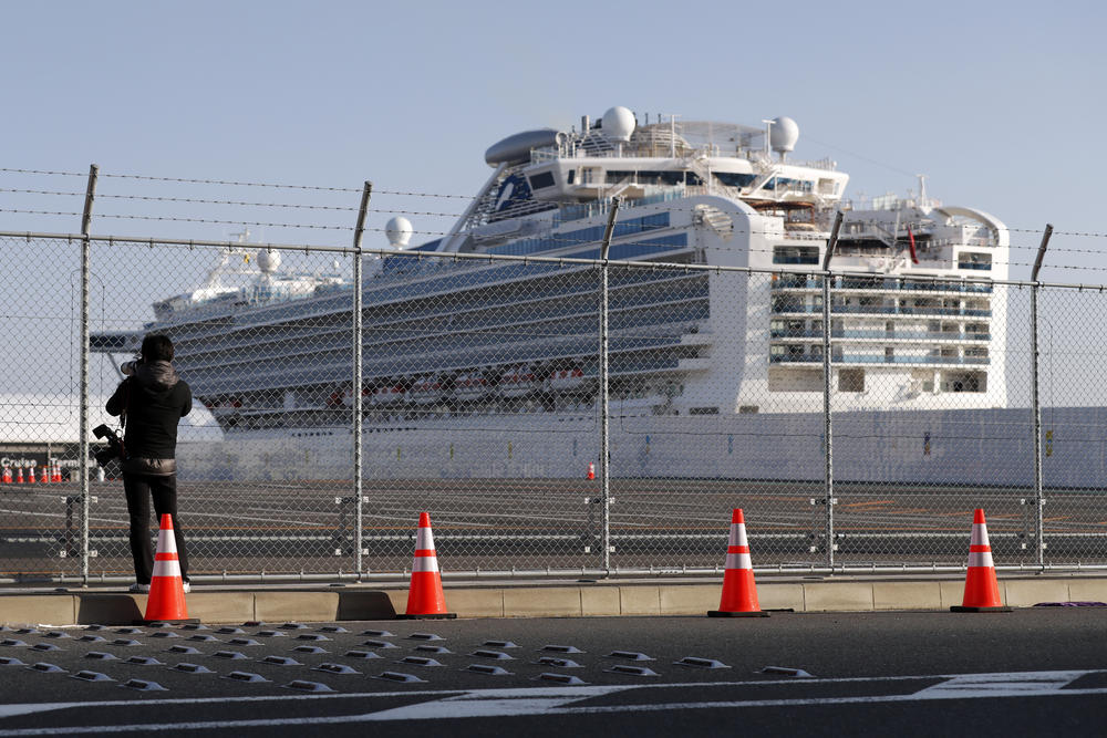 A photographer takes photos near the quarantined Diamond Princess cruise ship anchored at a port in Yokohama, near Tokyo, Friday, Feb. 21, 2020. Passengers tested negative for COVID-19 started disembarking since Wednesday.