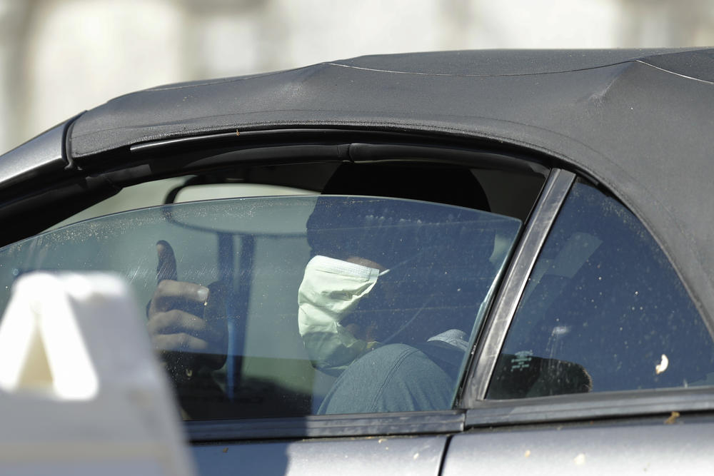 A person wearing a mask rolls down the window to ask about a COVID-19 testing site on Georgia Tech's campus, Monday, April 6, 2020, in Atlanta. 