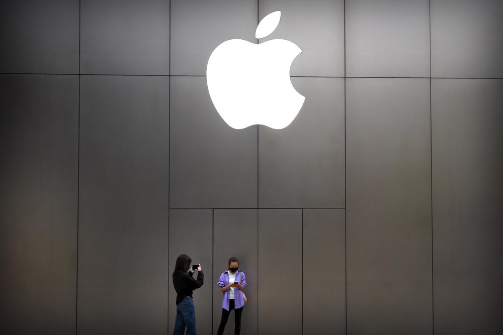 Women wear face masks to protect against the spread of the new coronavirus as they stand near an Apple store in Beijing, Friday, April 24, 2020.