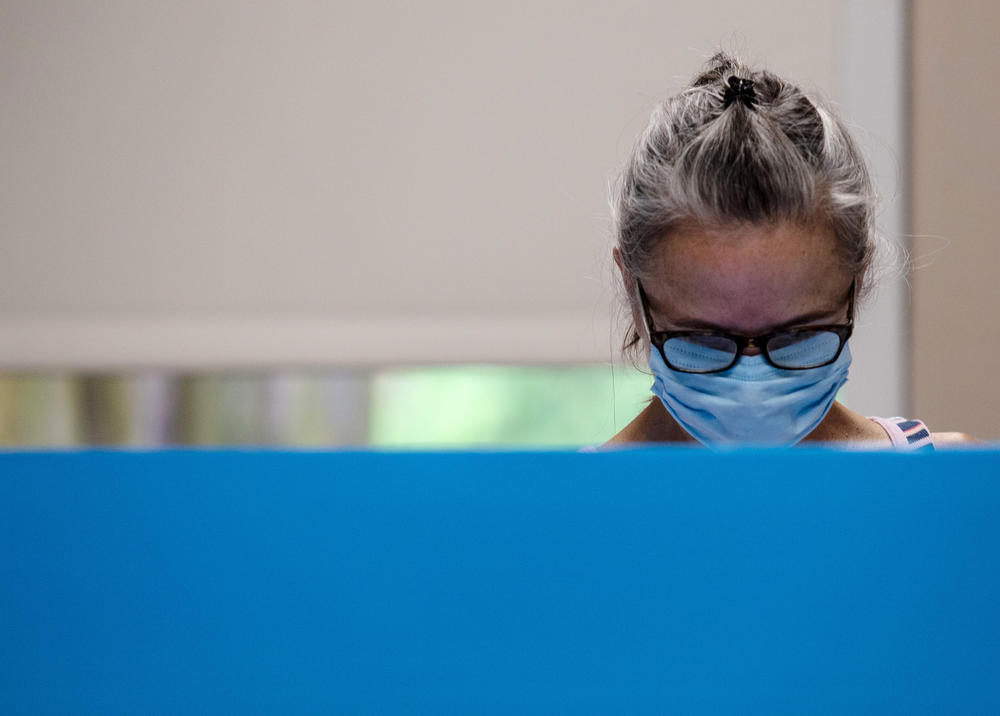 A voter wearing a protective mask is seen at the Dunwoody Library on Monday, May 18, 2020, in Dunwoody, Georgia. Georgians were greeted with a few new procedures as they participated in the first day of in-person early voting for the state's June primary.