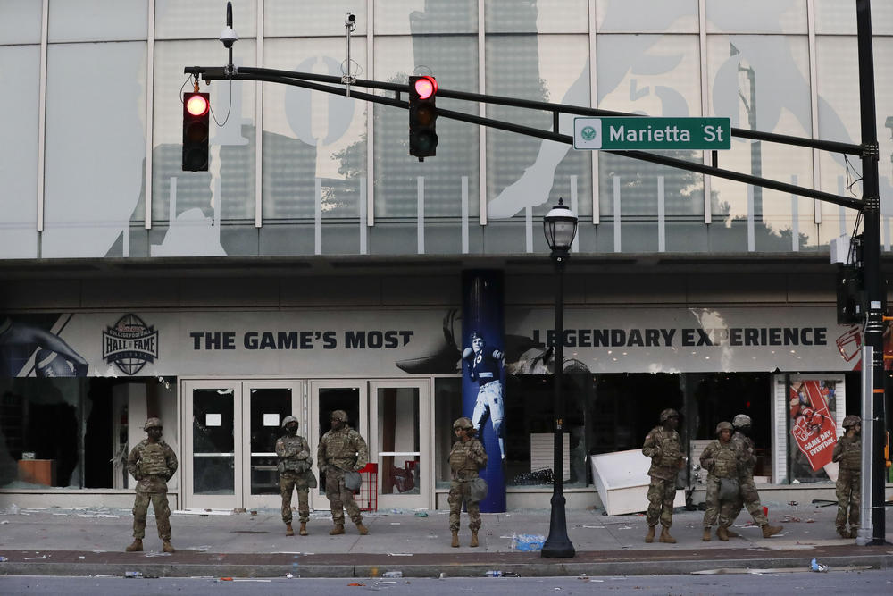 The Georgia National Guard lines up in front of the of the College Football Hall of Fame in the aftermath of a demonstration against police violence on Saturday, May 30, 2020, in Atlanta. (AP Photo/Brynn Anderson)