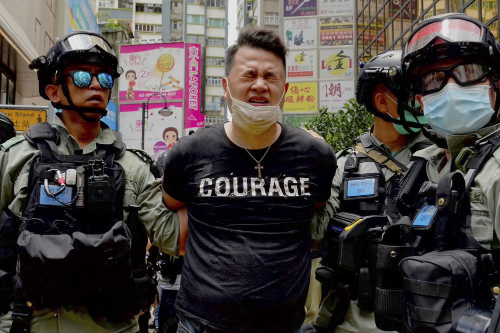 Police detain a protester after bering sprayed with pepper spray during a protest in Causeway Bay before the annual handover march in Hong Kong, Wednesday, July 1, 2020. 