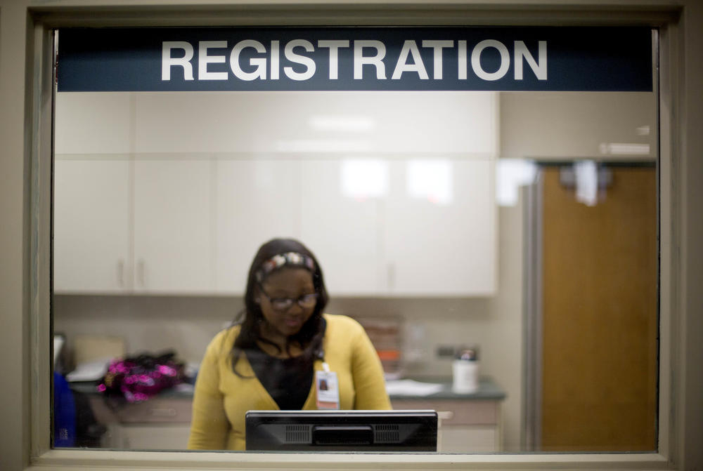 A worker is seen behind the registration window of the emergency room at Grady Memorial Hospital in Atlanta.
