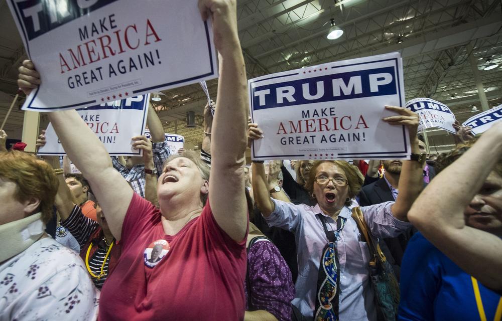 Supporters Kathleen Hastings, left, and Elizabeth Musngi, right, cheers Republican presidential candidate Donald Trump as he speaks during a campaign rally held at the North Atlanta Trade Center, Saturday, Oct., 10, 2015, in Norcross, Ga.