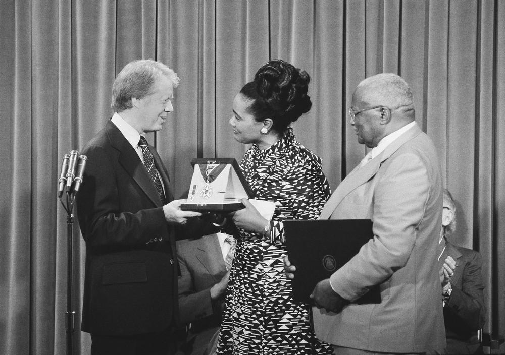 President Jimmy Carter presents the Medal of Freedom Award to Coretta King, wife of the late Dr. Martin Luther King, during a ceremony at the White House in 1977. At right is Martin Luther King, Sr., father of the slain civil rights leader.
