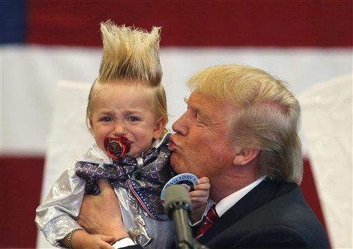Republican presidential candidate Donald Trump holds up a child he pulled from the crowd as he arrives to speak at a campaign rally in New Orleans, Friday, March 4, 2016.