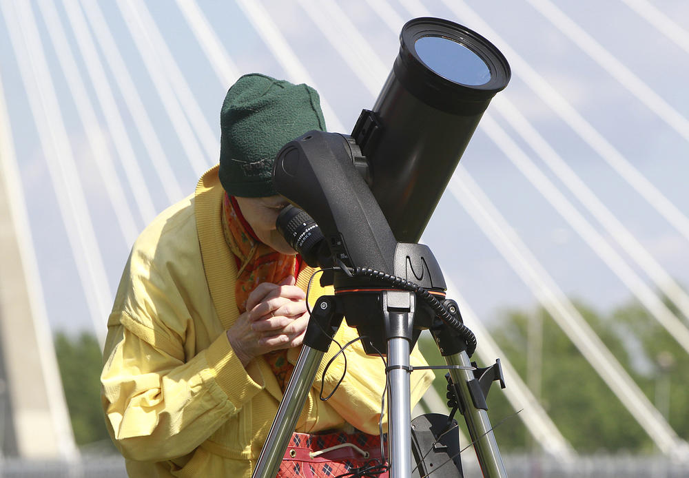 A woman watches through specially secured telescope as planet Mercury passes against the Earth and the Sun in a rare astronomical occurrence before the Copernicus Science Center in Warsaw, Poland, Monday, May 9, 2016.