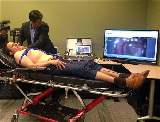 Manoel Coelho, a GlobalMed representative, uses a device with a camera to look at colleague Tim White's ear, displayed on monitor, during a June 22, 2015, demonstration of some of the technology and equipment options available for telehealth services. 