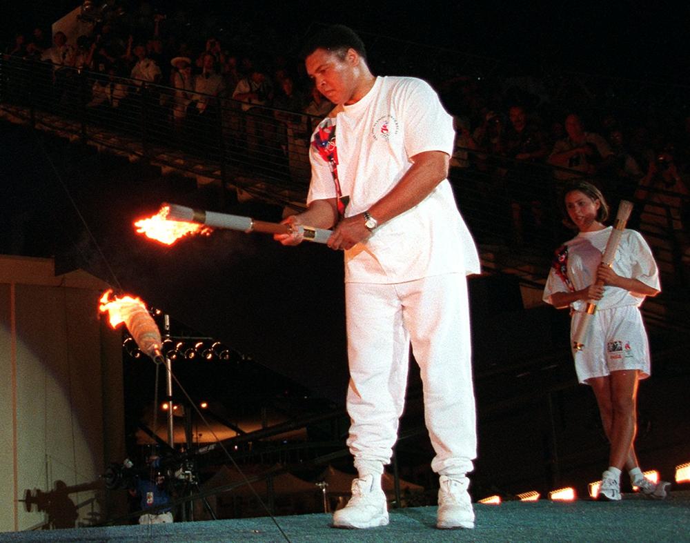American swimmer Janet Evans looks on as Muhammad Ali lights the Olympic flame during the 1996 Summer Olympic Games opening ceremony in Atlanta Friday, July 19, 1996.