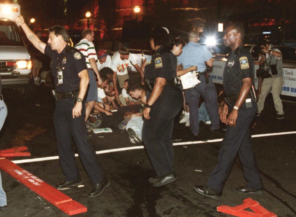 Emergency personnel and volunteers surround an injured person after an explosion in Atlanta's Centennial Olympic Park early Saturday morning July 27, 1996. 