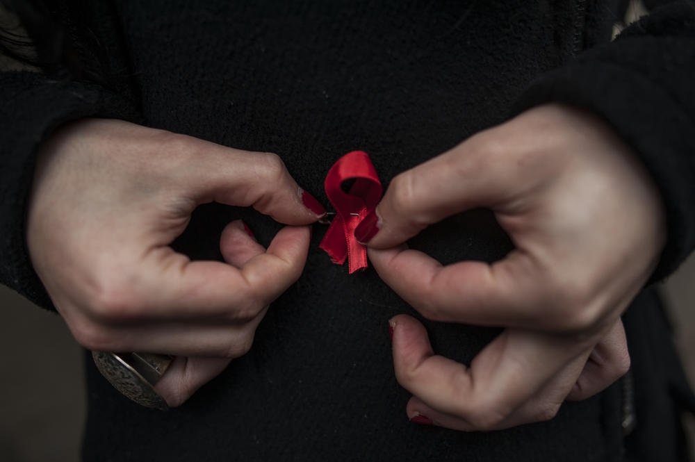 A woman adjusts a red ribbon, symbol of the fight against AIDS during a demonstration on World Aids Day, in Pamplona northern Spain, Monday, Dec. 1, 2014. 