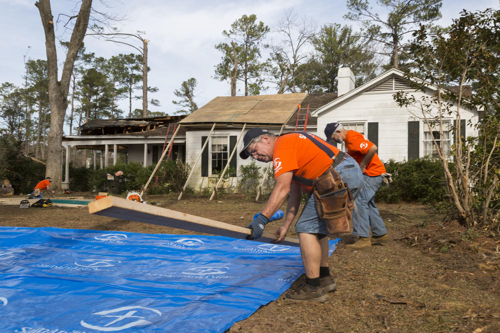 Volunteers with Samaritan's Purse, a disaster relief group associated with Franklin Graham Ministries, work on securing a storm damaged roof with a tarpaulin in Albany, Ga. 