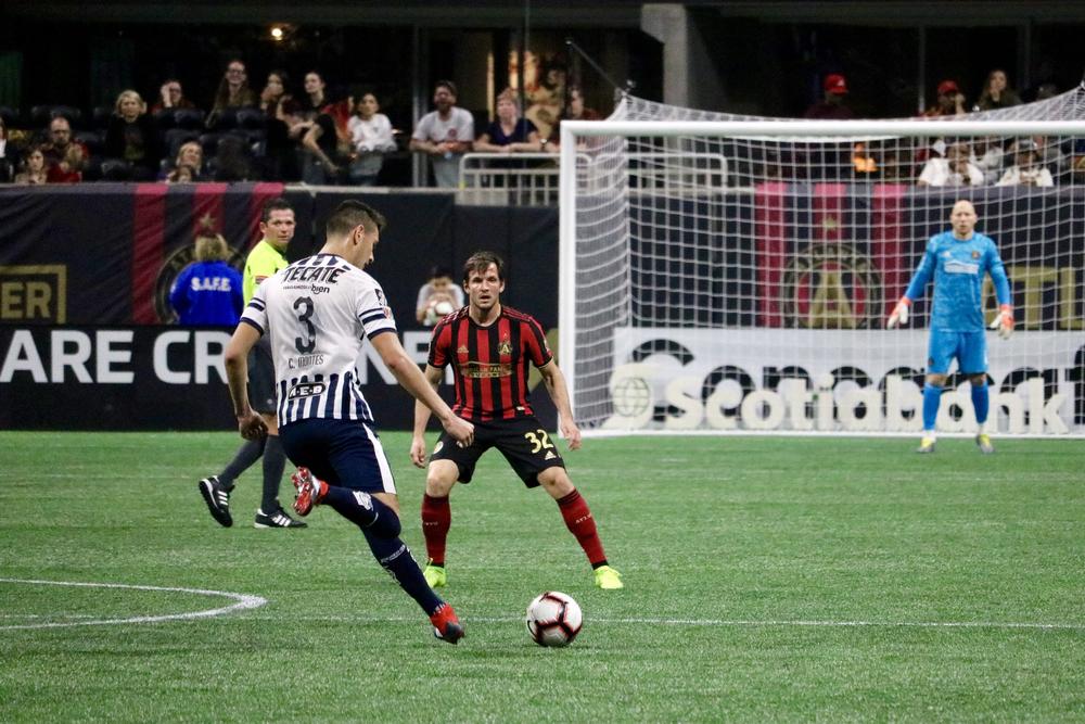 Atlanta United defender Mikey Ambrose challenges Monterrey defender CÃ©sar Montes while goalkeeper Brad Guzan gets set in the goal.