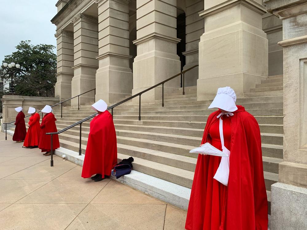 Women dressed in 'Handmaid's Tale' costumes stand outside the Georgia State Capitol in protest to 'Heartbeat Bill.'