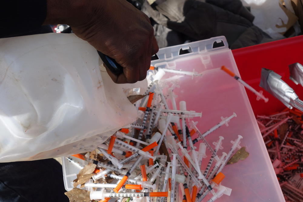 A client pours old needles from a water jug.