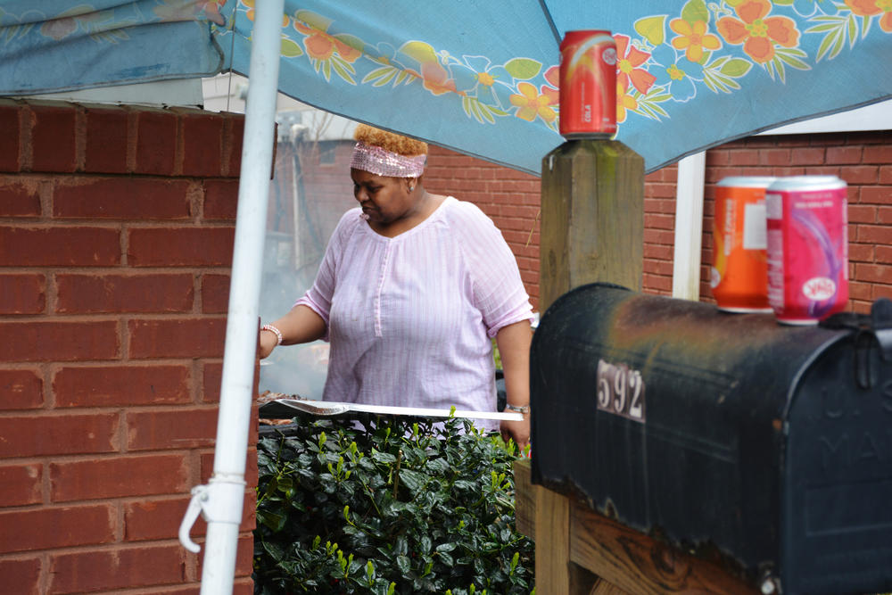 Alicia Anderson tends the grills at a family barbecue at her Vine City home.