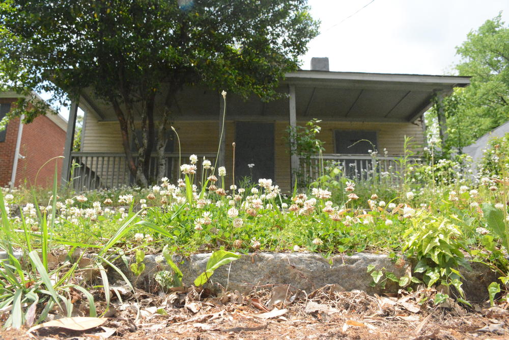 Weeds grow in the front yard of a boarded-up home in English Avenue.