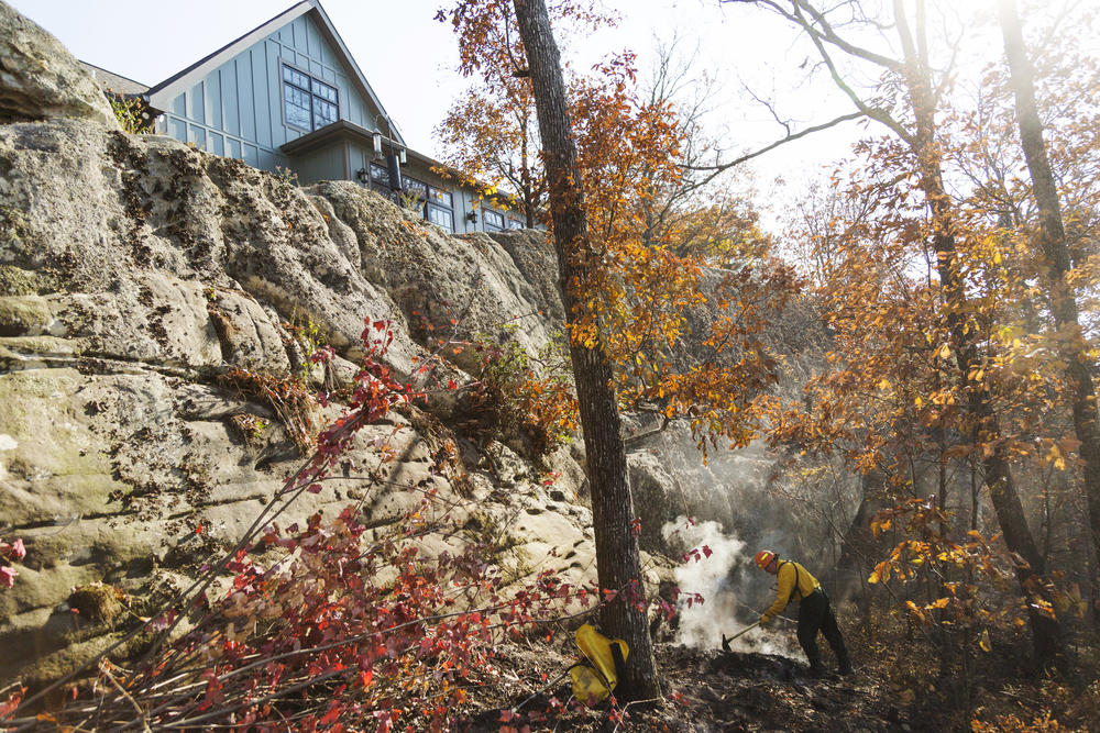 Hal Massie, a botanist turned Department of Natural Resources firefighter from Macon, works on a bit of smoldering fire just below a home on the brow of Lookout Mountain near the Georgia, Tennessee, and Alabama borders. Firefighting resources are stretched thin in Georgia with foresters, state scientists, and even firefighters from a prison training program on the ground. 