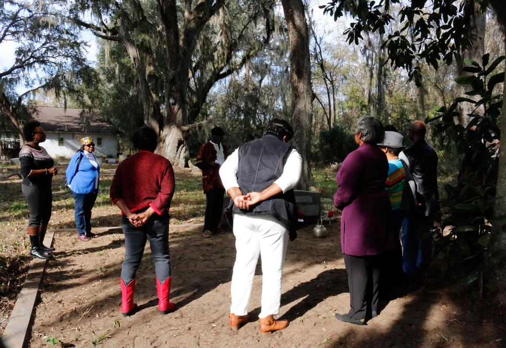 The family gathers around the headstone to honor their loved ones.