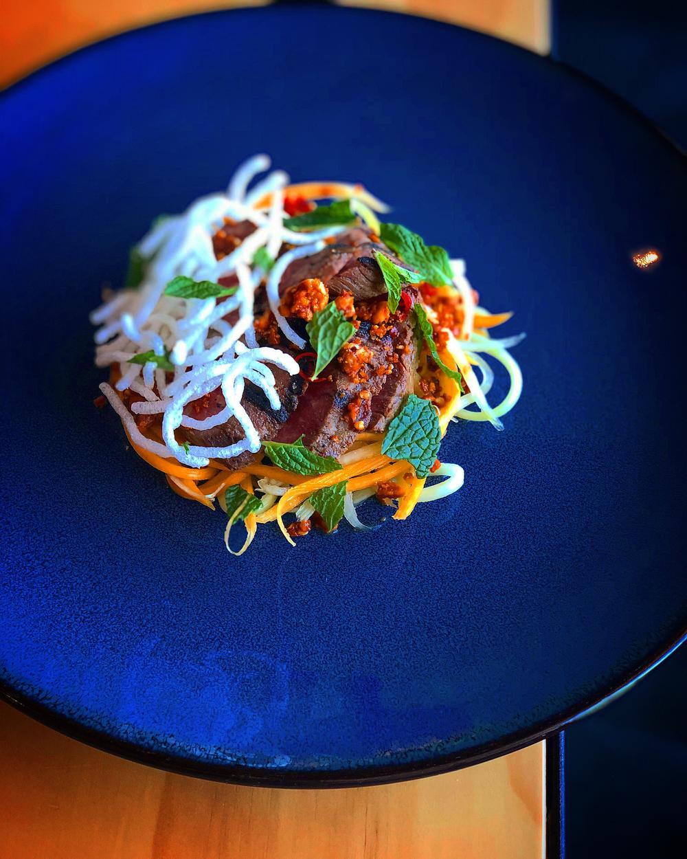 Chef Nolan Wynn's savory peanut brittle gives a sweet, salty and spicy topping to a papaya salad now available on Banshee's menu.