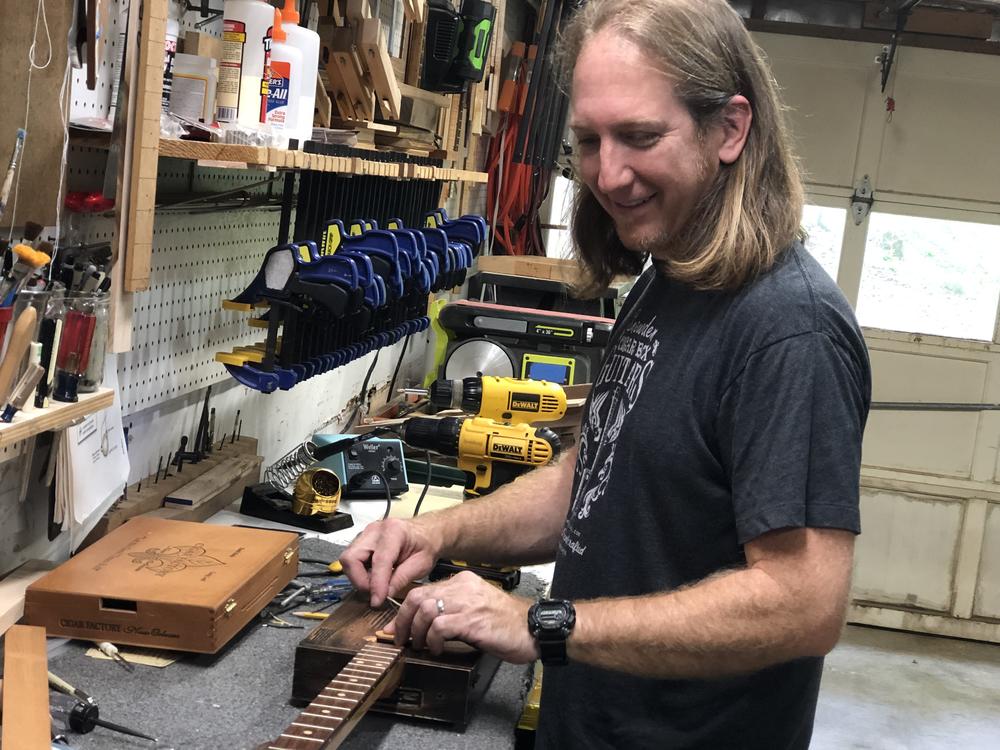 Mike Snowden in his Marietta home-based shop. He crafts and sells cigar box guitars.