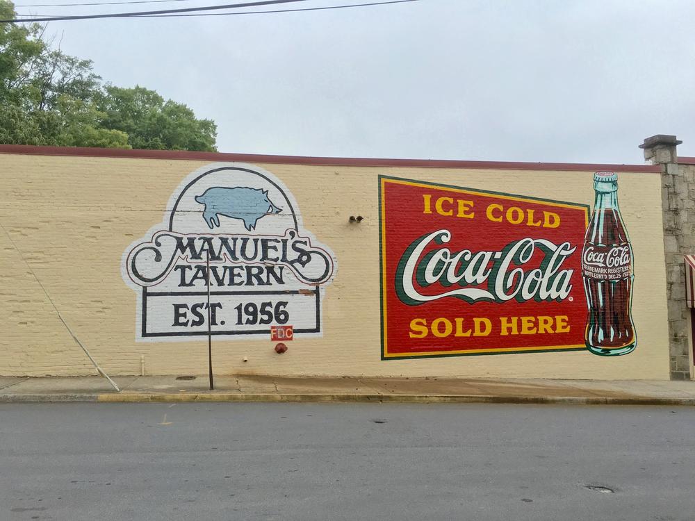 The newly-repainted signs advertising Manuel's Tavern and Coca-Cola.