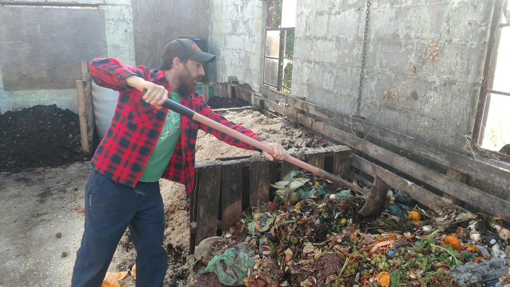 Brent Hall of Freewheel Farm mixes up a compost pile at his farm.