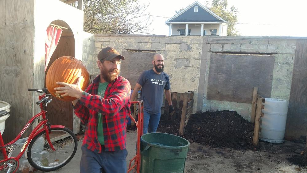 Brent Hall of Freewheel Farm (l) throws a pumpkin that Whit Whitmire (r) picked up during one of his stops. He is smashing the pumpkin to make it easier for it to absorb in a compost pile.
