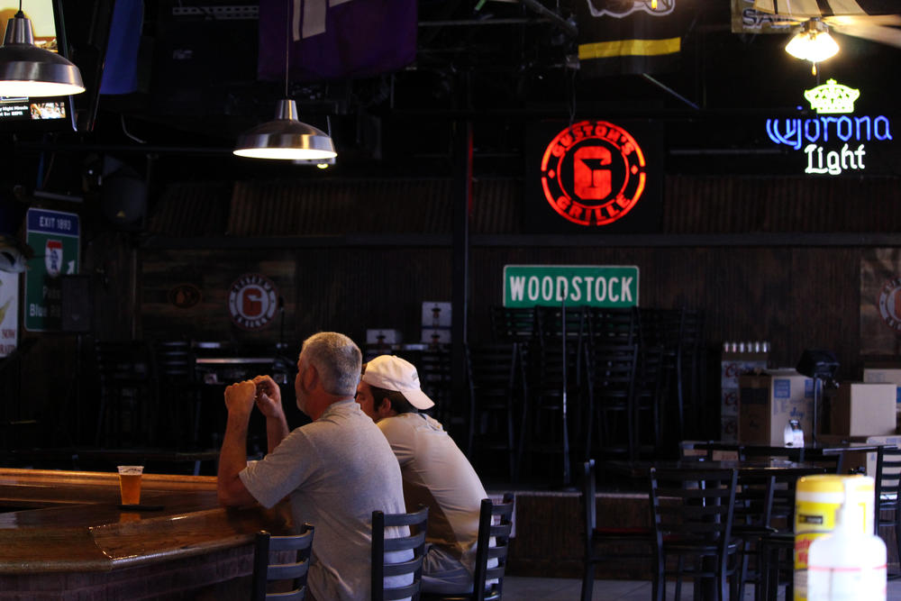 Doug (left) sits with his son at the Guston's Bar and Grille bar in Woodstock on the first days customers are allowed to dine indoors after some lockdown restrictions were lifted by Gov. Brian Kemp.