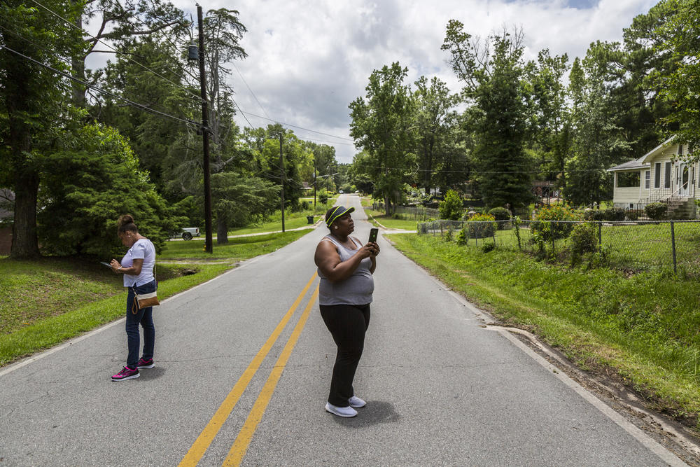 Karissa Coleman, center, and Teyona Little, left, use computer tablets in an East Macon neighborhood to conduct part of a survey of 33,000 land parcels meant to aid Macon-Bibb County's blight remediation efforts. 