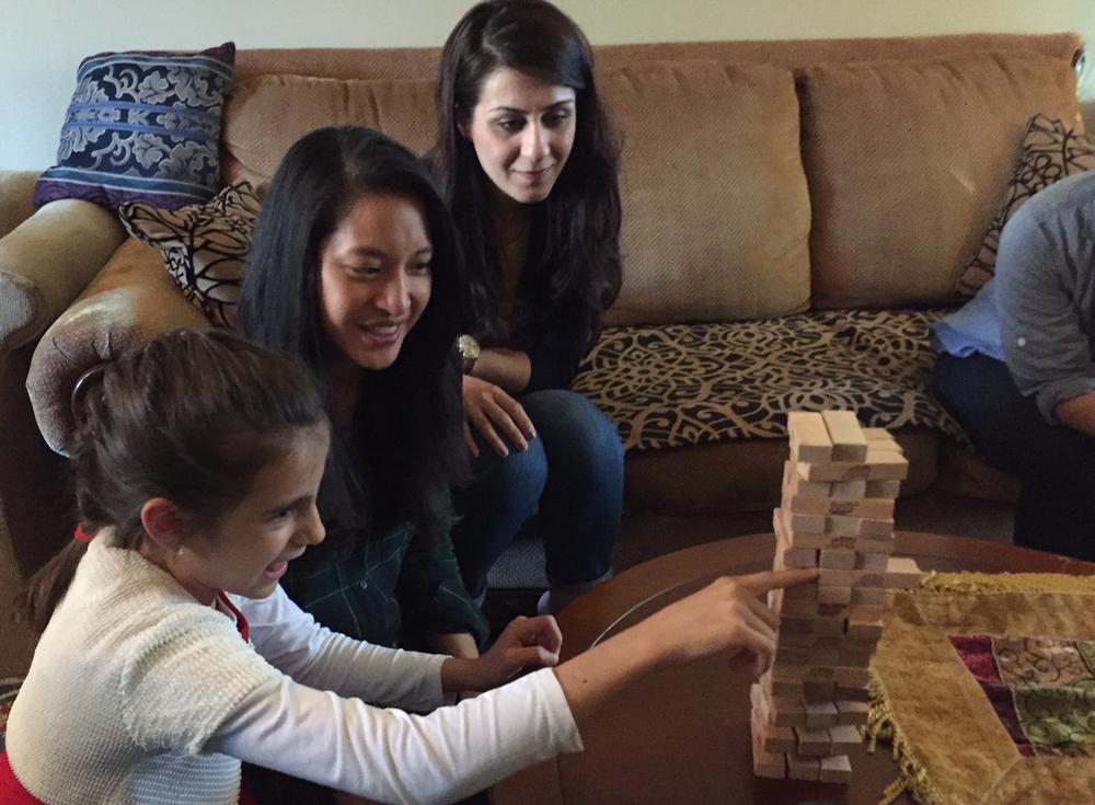 Bee Nguyen (m) works with Syrian refugees adjusting to life in the U.S. She plays a game of Jenga with Nawroz, 10, whose family arrived in Decatur, Georgia earlier this year. Watching on is Kurdeen Karim, who came to Georgia as a refugee in the late '90s.