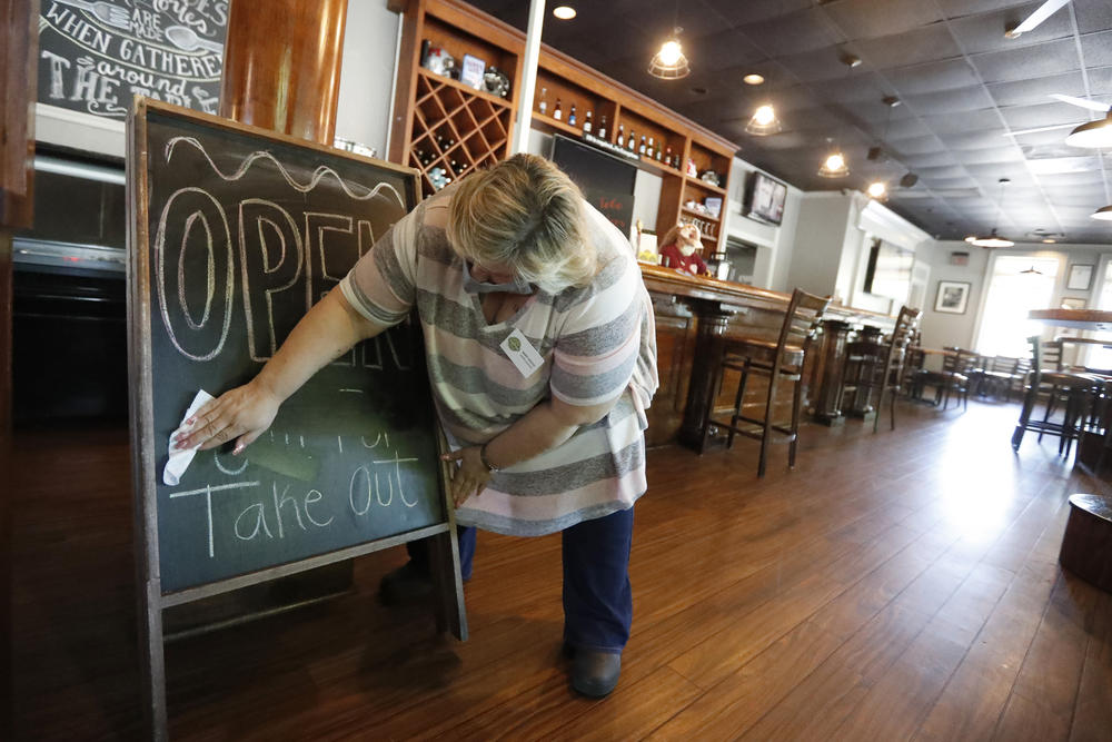 Mary Spoto, general manager of Madison Chop House Grille, changes the sign as she and her staff prepare to shift from take out only to dine-in service in April in Madison, Ga.