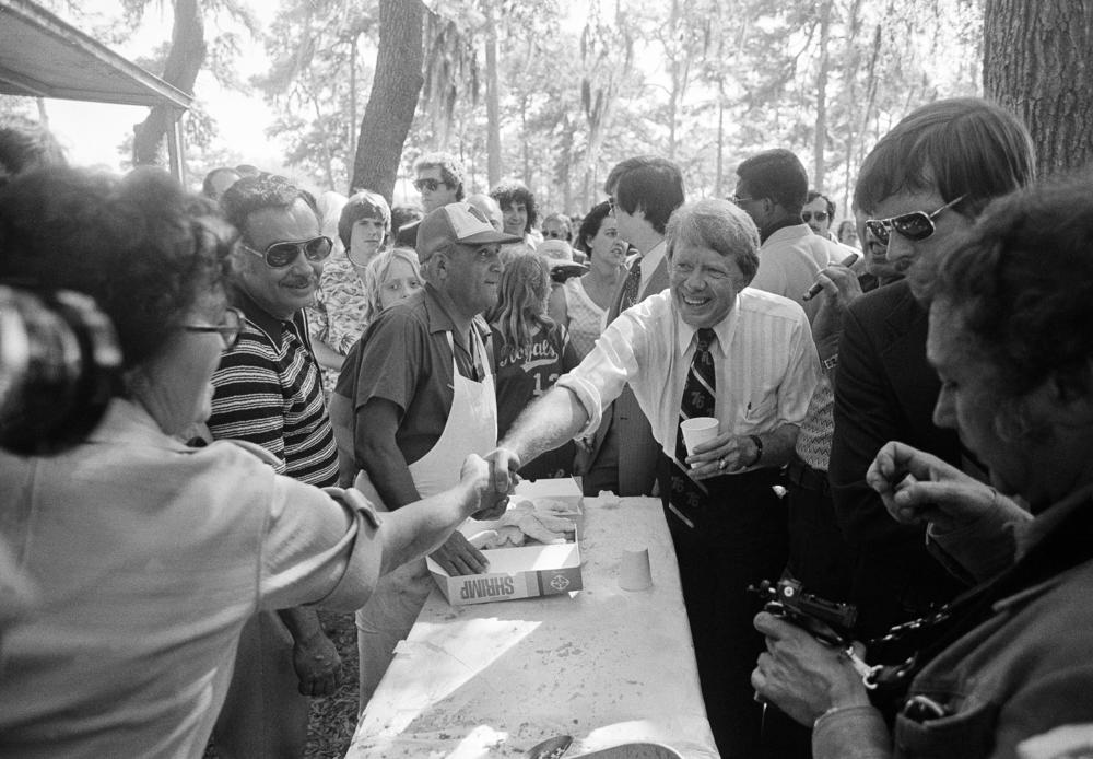 Jimmy Carter, right, Democratic presidential candidate, shakes hands and thanks the cooks at a fish fry and Carter rally in Tampa, Fla., March 7, 1976.