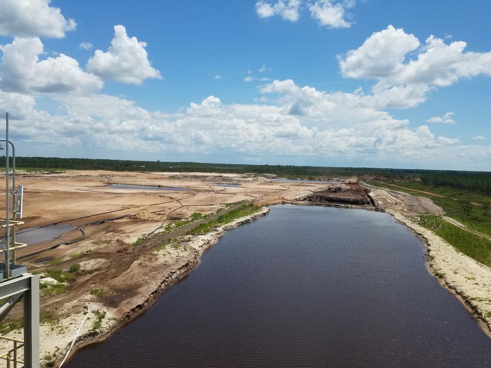 The current Southern Ionics mine. Beyond the canal (foreground) is the active portion, where workers are digging. The sandy area (left) has already been mined and is in the process of being filled back in. The topsoil will then be replaced and trees replanted. Twin Pines proposes to use a different mining method but would follow a similar process of mining followed by reclamation.