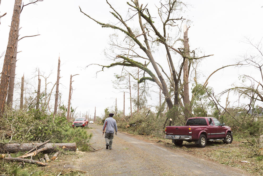 Torie Clemons walks up a road with an axe to start clearing trees from atop and trapped car in Albany, Ga. on January 23, 2017. 