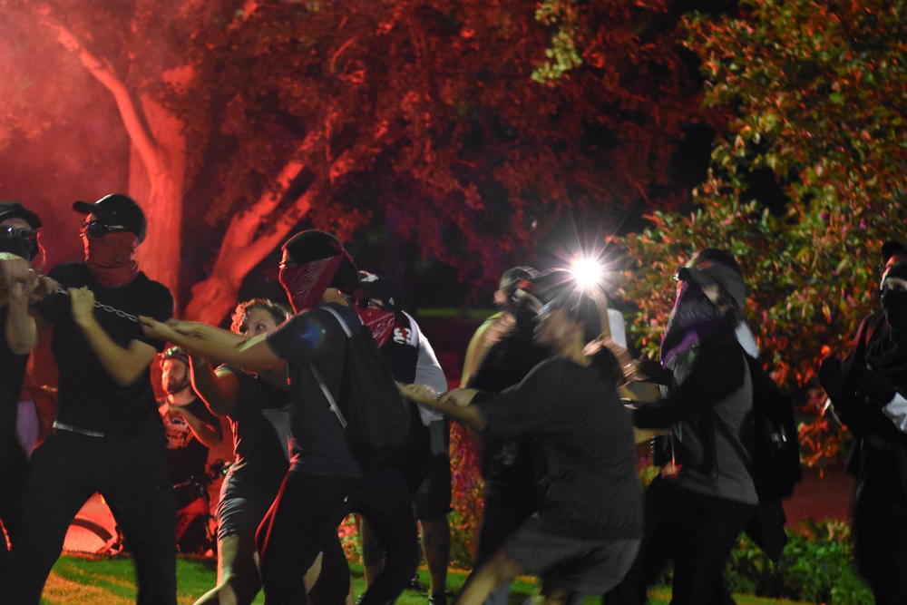 A group of masked anti-facist protestors attempt to pull down part of the Peace Monument statue in Piedmont Park.