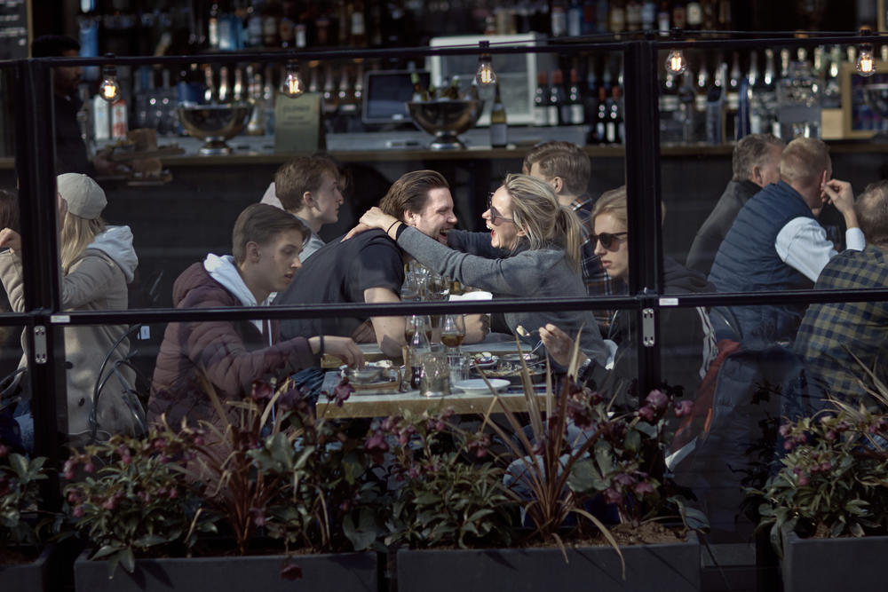 A couple hugs and laughs as they have lunch in a restaurant in Stockholm, Sweden. This photo, taken Apr. 4, 2020, illustrates Sweden's relatively relaxed response to coronavirus, in contrast with the lockdown approach taken by many other countries. 