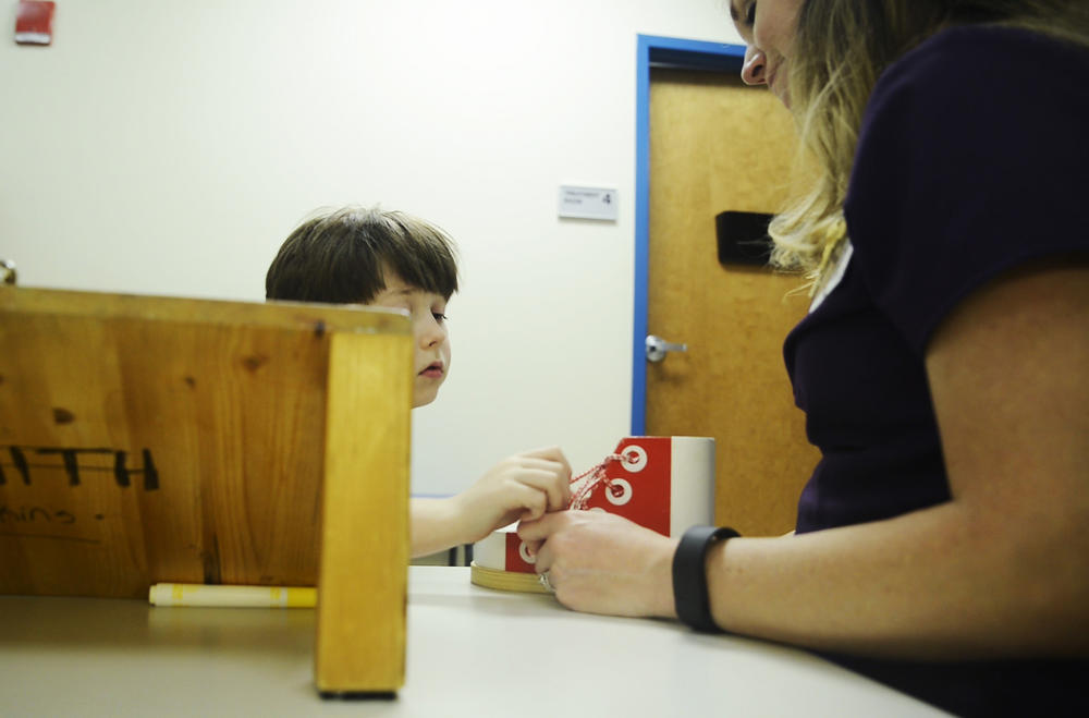 Alex Rayburn, seven,  practices tying and untying a shoe with the help of physical therapist Kathryn Staples at the Autism Center at Navicent Health in Macon. 