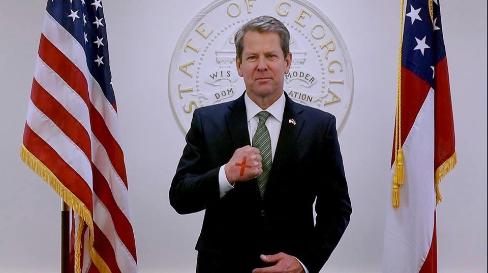 Gov. Brian Kemp poses with a red X on his hand to raise awareness for the 