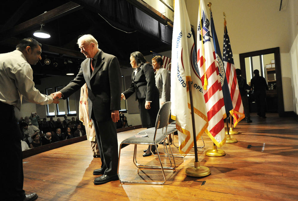 Former President Jimmy Carter congratulates one of the nearly 40 people sworn in as citizens at the Carter's old high school, now the Jimmy Carter National Historic Site in Plains, Thursday morning, January 2013. 