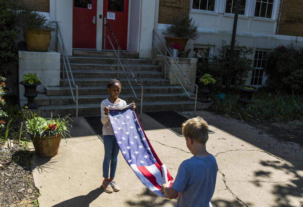 Summer Hardeman, left, and Xander Zimmerman fold the flag near the end of the school day at Atlanta Neighborhood Charter School. 