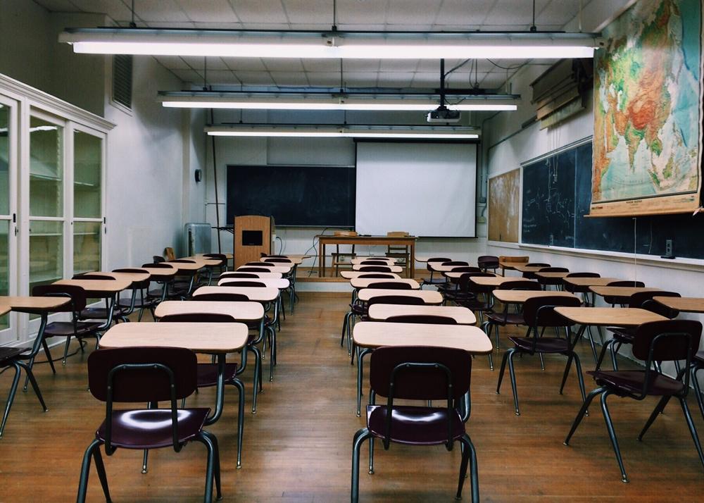 Desks sit empty in a classroom.