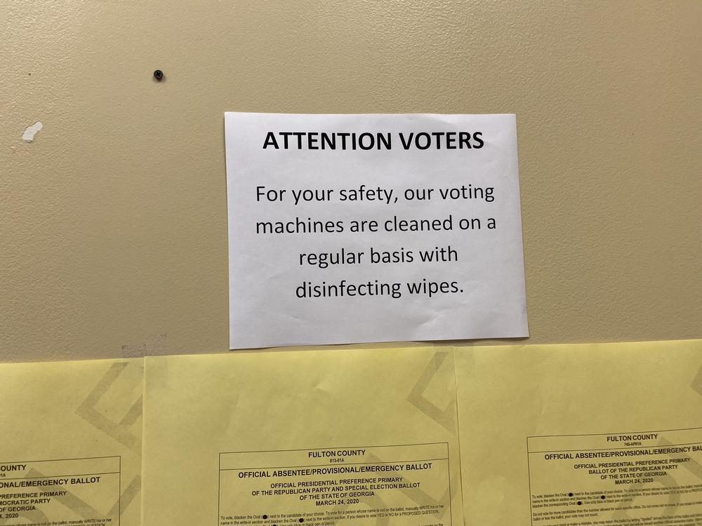 A sign about cleaning voting machines greets voters at the Fulton County Government Center polling place.