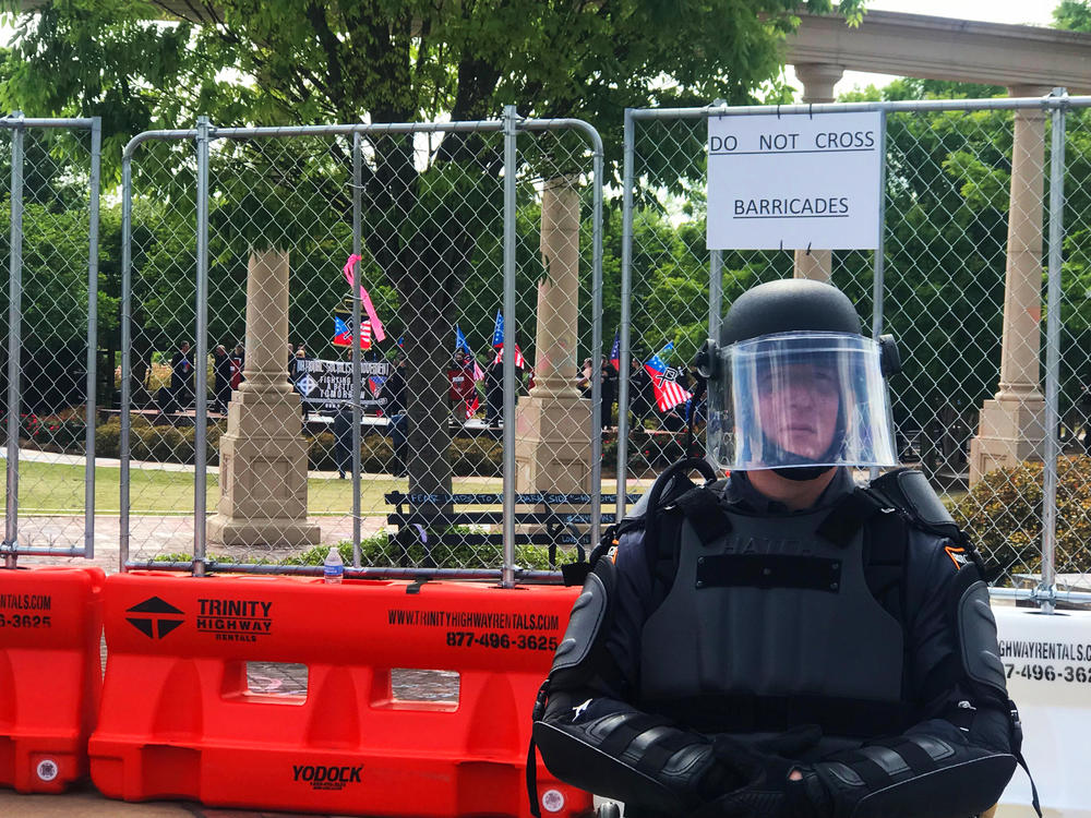 A Georgia State Patrol officer stands guard as members of the National Socialist Movement arrive in Newnan's Greenville Park under police escort. 