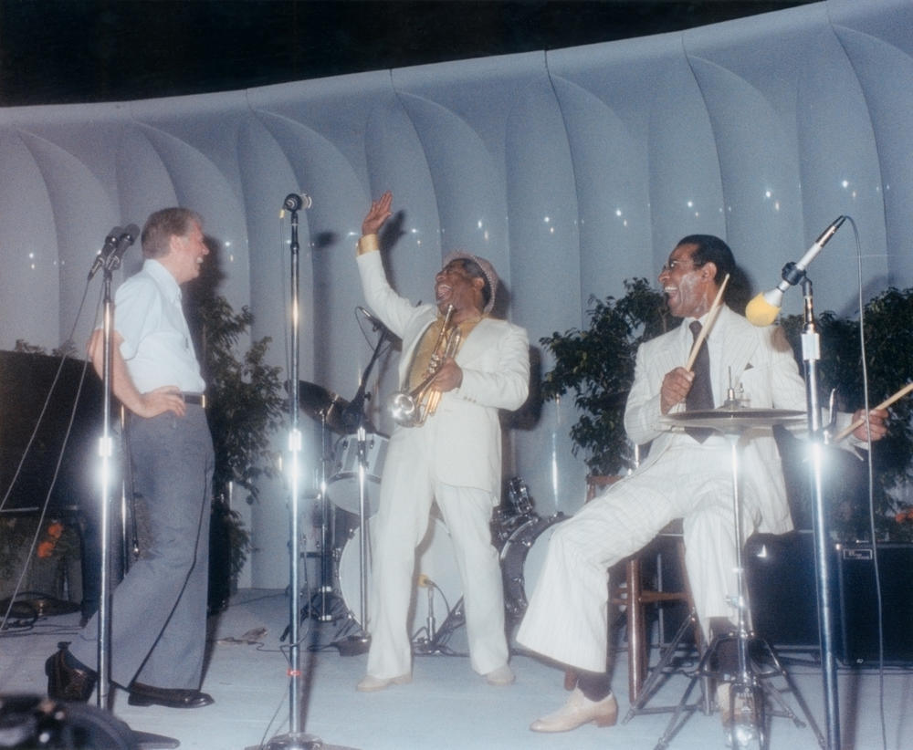 This photograph of President Jimmy Carter on stage at a White House jazz concert was taken on June 18, 1978. Carter appears in the photograph with trumpeter Dizzy Gillespie (center) and percussionist Max Roach (right).